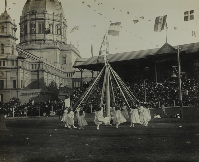 Children in 1901 dance around the May Pole in this traditional activity.